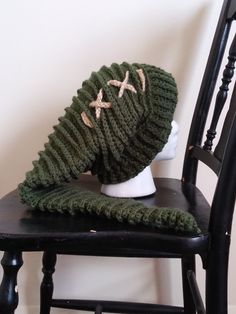 a green knitted hat sitting on top of a wooden chair next to a white mannequin head