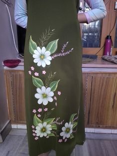 a woman standing in front of a counter wearing a green dress with white flowers on it