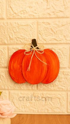 two orange pumpkins sitting on top of a wooden table next to a white brick wall