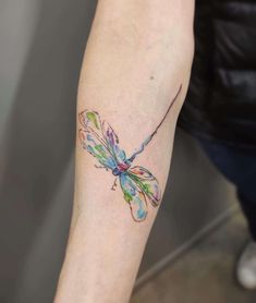 a colorful dragonfly tattoo on the arm