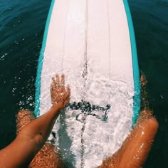 a person on a surfboard in the water with their hand up to the board