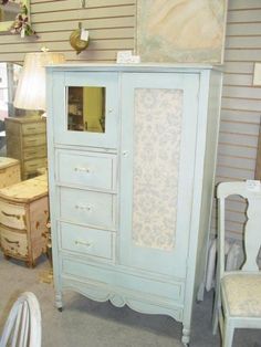 a blue armoire sitting next to a white chair