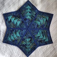 a close up of a blue quilt on a white table cloth with an intricate design