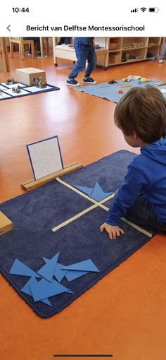 a young boy sitting on the floor playing with construction paper