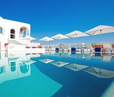 an empty swimming pool with lounge chairs and umbrellas in the sun on a clear day