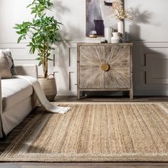 a living room with a couch, rug and potted plant on the sideboard