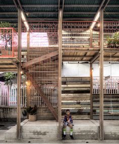 a young boy sitting on the steps in front of a building with metal railings