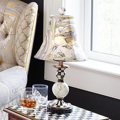 a lamp sitting on top of a table next to a glass filled with liquid and ice