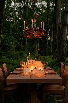 a dining table with candles on it in the woods