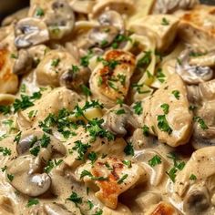 a pan filled with pasta and mushrooms covered in sauce, garnished with parsley