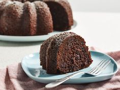 a chocolate bundt cake on a plate next to another bundt cake in the background