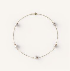 a bracelet with pearls and gold beads on a white background, the bead is attached to