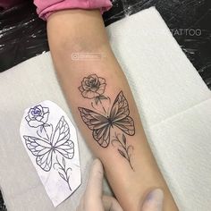 a woman with a tattoo on her arm is holding onto a flower and butterfly design