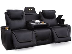 the theater seating is black and has two recliners on each side, one with a table in front of it