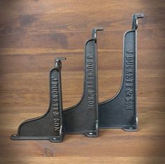 two black metal brackets sitting on top of a wooden table