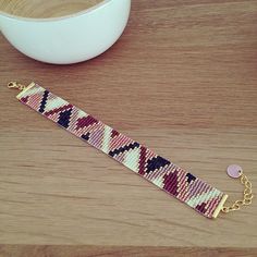 a bracelet sitting on top of a wooden table next to a white bowl and spoon