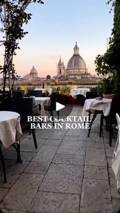 an outdoor dining area with tables and chairs on the patio, overlooking rome's dome