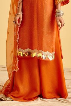 Tangerine orange kurta with mirror embroidery, bandhej print, lace detailing and bell sleeves. Paired with embroidered dupatta and sharara.
Components:3
Pattern:Embroidery,Printed
Type of Work:Mirror Embroidery
Neckline:Round
Sleeve Length:Flared Sleeves
Fabric:Kurta: Bandhani Print Organza, Sharara: Satin Shimmer, Dupatta: Organza
Color:Orange
Other Details:
Bandhej print
Mirror work
Note: Inner worn by the model is not for sale
Occasion:Sangeet,Wedding - Aza Fashions Organza Sharara, Bandhej Print, Print Mirror, Embroidery Kurta, Bandhani Print, Embroidery Neckline, Orange Mirror, Mirror Embroidery, Embroidered Dupatta