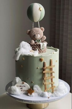 a teddy bear on top of a cake with clouds and stars in the air above it