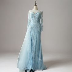 a light blue gown with long sleeves and beading on the skirt is displayed in front of a mannequin