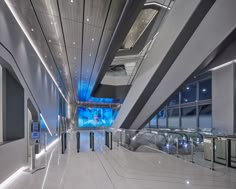 the inside of an airport terminal with glass and metal railings on either side of the escalator