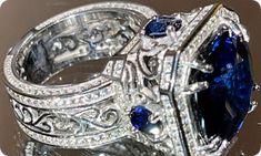 an ornately designed ring with blue and white stones on it's sides, surrounded by diamonds