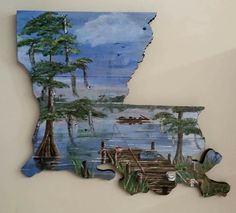 a piece of wood that has been cut into the shape of a state with trees and boats on it