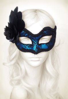 Venetian style masquerade mask covered black lace on metallic silver surface. Framed with black braided trim, small black rhinestones on the corners of the eyes. Decorated with black satin rose and black feathers. Your order will be delivered with online tracking by UPS or FedEx. Back surface is also covered with fabric for comfortable use. Ribbons are added both sides to tie. Base mask is made of paper mache. Standard size fits most (for women). This classical Venetian mask is perfect for any c Blue Masquerade Mask For Halloween Party, Blue Masquerade Mask For Halloween Costume Party, Blue Masks And Prosthetics For Halloween Costume Party, Blue Masquerade Mask For Halloween, Blue Halloween Masquerade Mask, Fitted Masquerade Mask For Mardi Gras, Blue Venetian Masquerade Mask For Party, Blue Party Eye Mask, Blue Eye Mask For Party