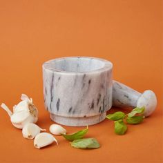 a marble mortar and garlic on an orange background