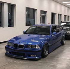 two cars parked in a garage next to each other near one another with windows on the wall