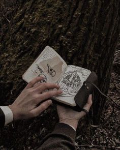 a person is writing on a book in the woods