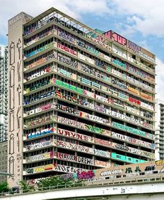 a very tall building with lots of windows and graffiti on it's side in the city