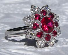 "This is a beautiful and striking MARIGOLD ring, featuring lab rubies and moissanites, set in white gold floral filigree that looks like sparkly lace on your finger! The center stone is a 6.5mm lab ruby. It is set in my MARIGOLD ring, featuring a delicate milgrain bezel surrounded by two rows of petals with floral filigree. The inside row of petals is made with lab rubies and outside petals hold moissanites. The gallery is designed to be completely open, making the ring very comfortable and easy Exquisite Brilliant-cut Ruby And Diamond Ring, Dazzling Ruby Diamond Ring, Exquisite Ruby Ring With Brilliant Cut Diamond, Exquisite Ruby Ring With Diamond Accent Stones, Dazzling Ruby Ring With Diamond Prong Setting, Dazzling Ruby Ring With Diamond Accents, Exquisite Ruby Ring With Accent Stones For Wedding, Exquisite Ruby Ring With Diamond Accents, Wedding Ruby Ring With Platinum Accent Stones