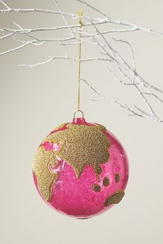 a pink and gold ornament hanging from a tree branch with white branches in the background