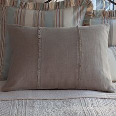 a bed with two pillows on top of it next to a lamp and window sill