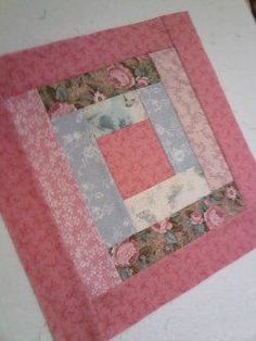 a close up of a pink and blue patchwork quilt on a white table cloth