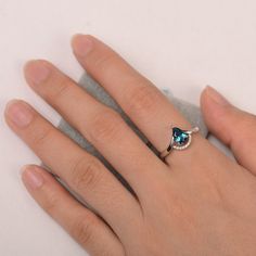 a woman's hand with a ring on it and a blue stone in the middle