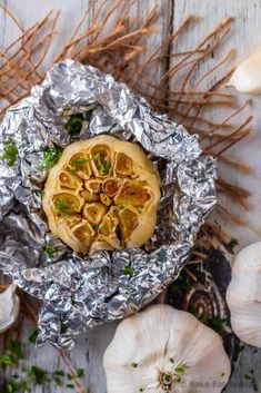 an overhead view of some food on tin foil and garlic sprouts around it