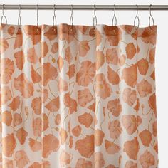 an orange flowered curtain hanging from a metal rod