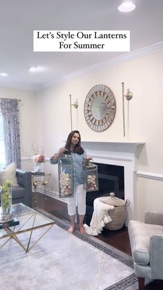 a woman standing in front of a fire place holding up some pictures on the wall