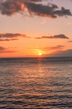 the sun is setting over the ocean with some clouds in the sky and one boat out on the water