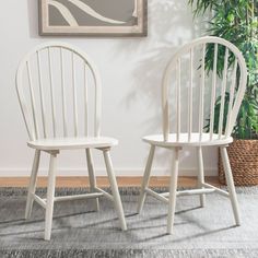 two white chairs sitting next to each other in front of a painting on the wall