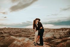 a man and woman standing on top of a mountain kissing in the middle of nowhere