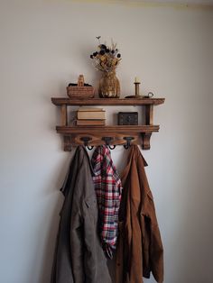 a coat rack with coats hanging on it and a vase filled with flowers next to it