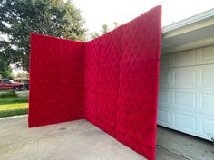 a red screen sitting in the middle of a driveway next to a white garage door