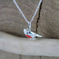 A firm British favourite, our perfect sterling silver Robin necklace is bursting with personality, with his beautiful red enamel breast and will bring a cheer to the dullest winter days. Perfect for a present to yourself or a friend and will add colour to your Festive Outfits. Matching drop earrings also available to complete your look. Sterling silver Coloured enamel detail High shine finish Robin measures 13mm across Made From recycled sterling silver Adjustable 16-18" sterling silver chain Un Red Enamel Charm Necklaces For Gifts, Silver Enamel Charm Necklace For Gift, Red Sterling Silver Pendant Charm Necklace, Valentine's Day Red Sterling Silver Charm Necklace, Robin Necklace, Robin Red Breast, Festive Outfits, Outfits Matching, Bee Necklace