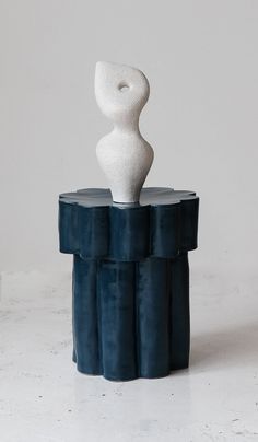 a white and black sculpture sitting on top of a blue table next to a wall