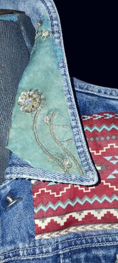 a piece of fabric with flowers on it sitting in the pocket of a jean jacket