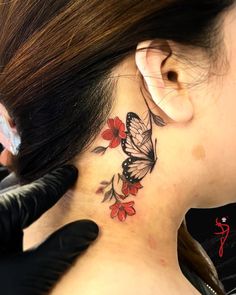 a woman with a butterfly tattoo on her neck and behind the ear is a red flower