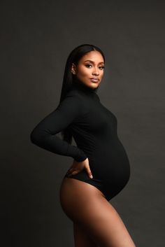 a black and white photo of a pregnant woman in tights with her hands on her hips